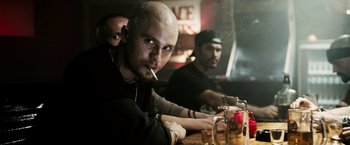 Movie still from “Death Sentence” (2007), directed by James Wan – A group of men sitting at a table with drinks and a cigarette; Close Up shot, Over the shoulder angle