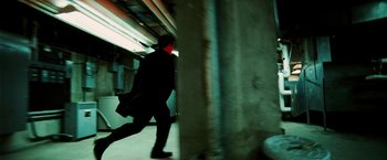 Movie still from “Death Sentence” (2007), directed by James Wan – A man in a black suit and a red mask walking down a street; Wide shot, Low angle
