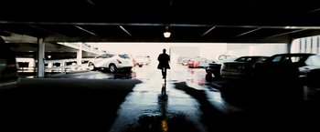 Movie still from “Death Sentence” (2007), directed by James Wan – A person walking in a parking lot with cars parked on the ground; Wide shot, Low angle
