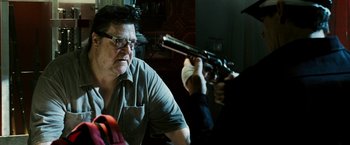 Movie still from “Death Sentence” (2007), directed by James Wan – A man sitting in front of another man holding a gun; Close Up shot, Over the shoulder angle