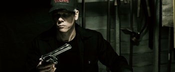 Movie still from “Death Sentence” (2007), directed by James Wan – A man holding a gun while wearing a baseball cap; Close Up shot, Low angle