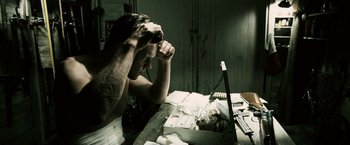 Movie still from “Death Sentence” (2007), directed by James Wan – A man sitting in front of a laptop computer on top of a desk; Medium shot, High angle