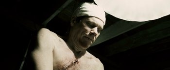 Movie still from “Death Sentence” (2007), directed by James Wan – A man with a bandage on his head and chest; Close Up shot, Low angle