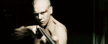 Movie still from “Death Sentence” (2007), directed by James Wan – A shirtless man holding a gun in a dark room; Close Up shot, Low angle