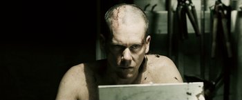 Movie still from “Death Sentence” (2007), directed by James Wan – A man with a shaved head looking at a laptop; Close Up shot, Over the shoulder angle