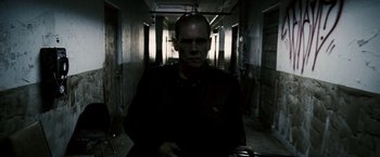 Movie still from “Death Sentence” (2007), directed by James Wan – A man standing in a dark hallway holding a gun; Medium shot, Low angle