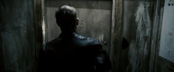 Movie still from “Death Sentence” (2007), directed by James Wan – A man in a leather jacket standing in front of a door; Close Up shot, Over the shoulder angle