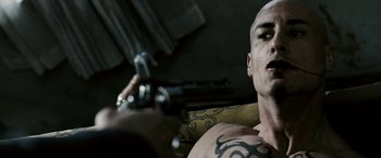 Movie still from “Death Sentence” (2007), directed by James Wan – A man with a tattoo is holding a gun in his hand; Close Up shot, Over the shoulder angle