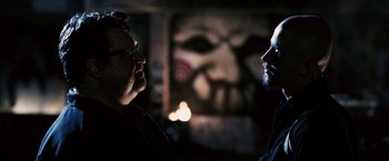 Movie still from “Death Sentence” (2007), directed by James Wan – Two men talking in front of a painting of a clown; Close Up shot, Over the shoulder angle