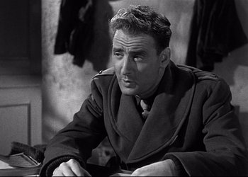 Movie still from “Decision Before Dawn” (1951), directed by Anatole Litvak – An old photo of an older man in a trench coat; Close Up shot, Over the shoulder angle