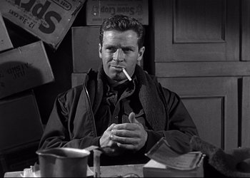 Movie still from “Decision Before Dawn” (1951), directed by Anatole Litvak – A man sitting at a table with a cigarette in his mouth; Medium shot, Low angle