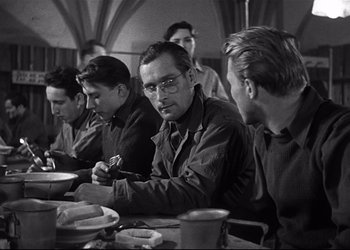 Movie still from “Decision Before Dawn” (1951), directed by Anatole Litvak – A black and white photo of a group of men sitting at a table; Medium shot, Over the shoulder angle