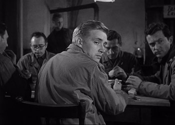 Movie still from “Decision Before Dawn” (1951), directed by Anatole Litvak – Black and white photograph of men sitting around a table; Medium shot, Over the shoulder angle