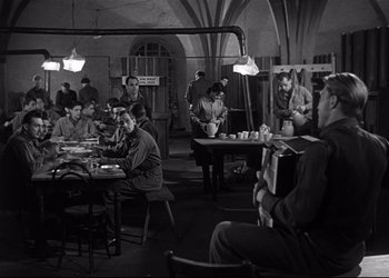 Movie still from “Decision Before Dawn” (1951), directed by Anatole Litvak – A black and white photo of people sitting at a table; Wide shot, High angle