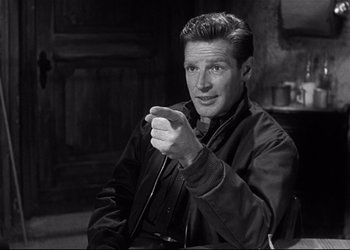 Movie still from “Decision Before Dawn” (1951), directed by Anatole Litvak – Black and white photograph of a man holding a pen; Medium shot, Over the shoulder angle