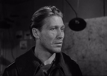 Movie still from “Decision Before Dawn” (1951), directed by Anatole Litvak – Black and white photograph of a man with long blonde hair; Close Up shot, Low angle