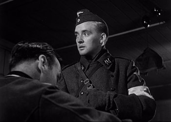 Movie still from “Decision Before Dawn” (1951), directed by Anatole Litvak – A man in a military uniform talking to another man; Close Up shot, Low angle