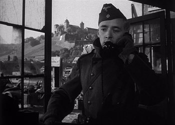 Movie still from “Decision Before Dawn” (1951), directed by Anatole Litvak – A man in a military uniform talking on a cell phone; Medium shot, Low angle