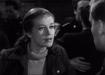 Movie still from “Decision Before Dawn” (1951), directed by Anatole Litvak – A black - and - white photo of a woman in a crowd; Close Up shot, Over the shoulder angle