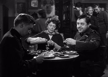 Movie still from “Decision Before Dawn” (1951), directed by Anatole Litvak – A group of people sitting around a table; Medium shot, Low angle