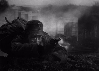 Movie still from “Decision Before Dawn” (1951), directed by Anatole Litvak – A man in a military uniform is holding a gun; Medium shot, Low angle