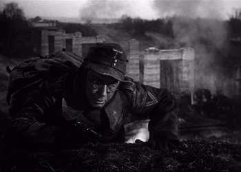 Movie still from “Decision Before Dawn” (1951), directed by Anatole Litvak – A man wearing a hat is laying on the ground; Medium shot, Low angle