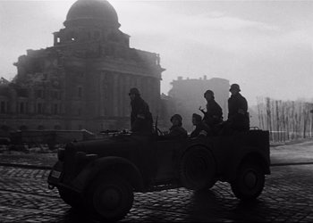 Movie still from “Decision Before Dawn” (1951), directed by Anatole Litvak – An old photo of men riding in an army vehicle; Wide shot, Low angle