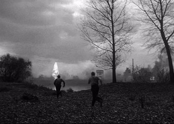 Movie still from “Decision Before Dawn” (1951), directed by Anatole Litvak – Two people are running in a field near a tree; Extreme Wide shot, High angle