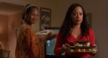 Movie still from “Deliver Us from Eva” (2003), directed by Gary Hardwick – Two women are holding trays of food in a room; Medium shot, Over the shoulder angle