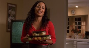 Movie still from “Deliver Us from Eva” (2003), directed by Gary Hardwick – A woman in a red shirt is holding two trays of food; Medium shot, Over the shoulder angle