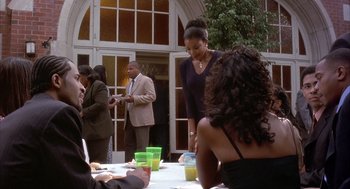 Movie still from “Deliver Us from Eva” (2003), directed by Gary Hardwick – A group of people sitting at a table with drinks; Medium shot, Over the shoulder angle