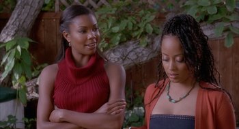Movie still from “Deliver Us from Eva” (2003), directed by Gary Hardwick – Two young women standing next to each other in a garden; Medium shot, Over the shoulder angle
