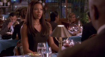 Movie still from “Deliver Us from Eva” (2003), directed by Gary Hardwick – A woman sitting at a table with a plate in front of her; Medium shot, Over the shoulder angle