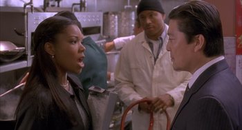 Movie still from “Deliver Us from Eva” (2003), directed by Gary Hardwick – A group of people standing around in a kitchen; Medium shot, Over the shoulder angle