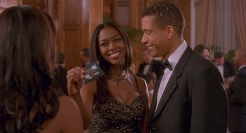 Movie still from “Deliver Us from Eva” (2003), directed by Gary Hardwick – A man and a woman in a black dress holding up a card; Medium shot, Over the shoulder angle