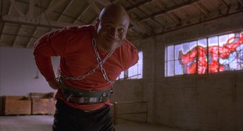 Movie still from “Deliver Us from Eva” (2003), directed by Gary Hardwick – A bald man in a red shirt and a chain around his neck; Medium shot, Low angle