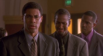 Movie still from “Deliver Us from Eva” (2003), directed by Gary Hardwick – A man in a suit and tie standing next to another man in a suit and tie; Close Up shot, Over the shoulder angle