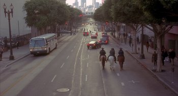 Two people on horseback ride down the street