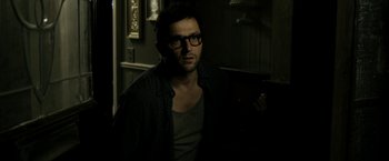 Movie still from “Deliver Us from Evil” (2014), directed by Scott Derrickson – A man with glasses is standing in a dark room; Medium shot, Over the shoulder angle