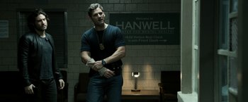 Movie still from “Deliver Us from Evil” (2014), directed by Scott Derrickson – A man standing in front of a wall with his arms crossed; Medium shot, Over the shoulder angle