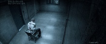 Movie still from “Deliver Us from Evil” (2014), directed by Scott Derrickson – A man sitting on a chair in a dark room; Wide shot, High angle