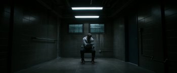 Movie still from “Deliver Us from Evil” (2014), directed by Scott Derrickson – A man sitting on a chair in a dark room; Wide shot, High angle