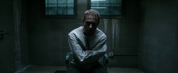 Movie still from “Deliver Us from Evil” (2014), directed by Scott Derrickson – A man sitting on a chair with his arms crossed; Medium shot, High angle