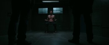 Movie still from “Deliver Us from Evil” (2014), directed by Scott Derrickson – A man sitting on a chair in a dark room; Wide shot, Low angle