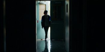 Movie still from “Demonic” (2021), directed by Neill Blomkamp – A woman walking through a door way in the dark; Wide shot, Low angle