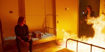 Movie still from “Demonic” (2021), directed by Neill Blomkamp – A person sitting on a bed in a room; Wide shot, High angle