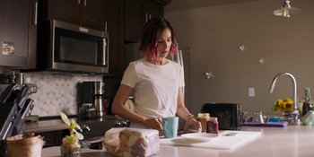 Movie still from “Demonic” (2021), directed by Neill Blomkamp – A woman in a kitchen preparing a meal; Medium shot, Over the shoulder angle