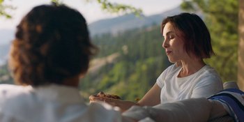 Movie still from “Demonic” (2021), directed by Neill Blomkamp – A woman holding a piece of food in her hands; Medium shot, Over the shoulder angle