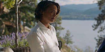 Movie still from “Demonic” (2021), directed by Neill Blomkamp – A woman sitting at a table holding a glass of wine; Medium shot, Over the shoulder angle