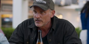 Movie still from “Demonic” (2021), directed by Neill Blomkamp – A person wearing a hat and holding a bottle; Close Up shot, Over the shoulder angle